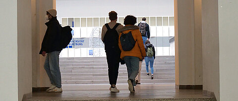 Studierende laufen im Unigebäude am Sanderring die Treppen hoch zur Vorlesung.