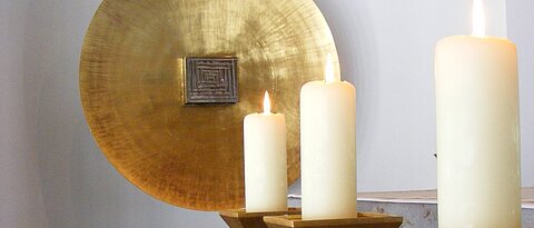 Detailansicht aus der Kilianskapelle, drei Kerzen vor einer großen goldenen Scheibe vor der der Tabernakel ist