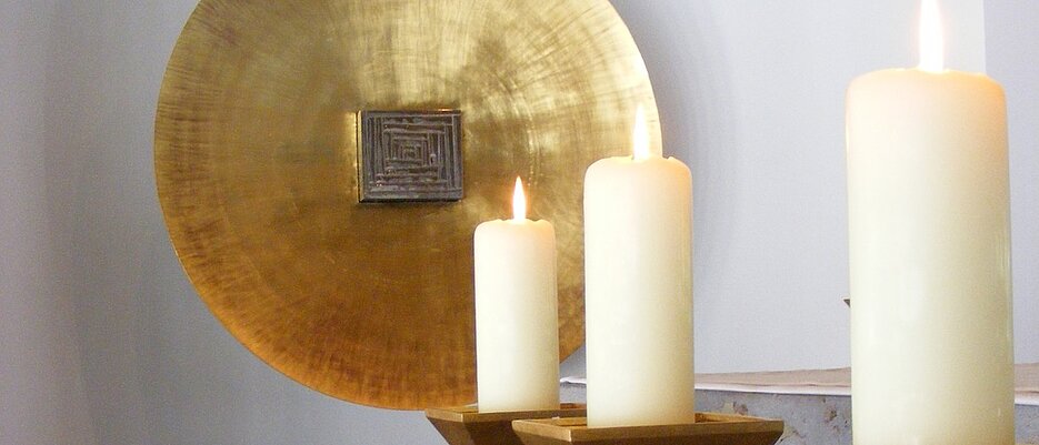 Detailansicht aus der Kilianskapelle, drei Kerzen vor einer großen goldenen Scheibe vor der der Tabernakel ist