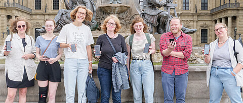 Das Team des Lehrstuhls für deutsche Philologie auf einem Rundgang durch Würzburg mit der neuen App – hier vor einer Station an der Residenz.