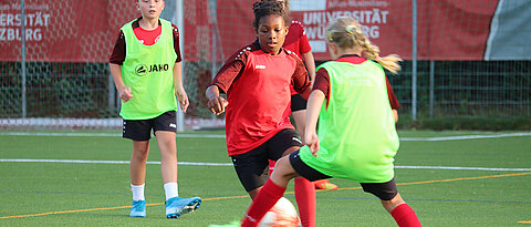 Mädchen auf dem Fußballplatz im Zweikampf um den Ball.