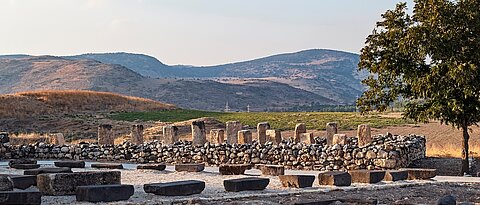 ruins of an israelite stone storehouse made with pillars and columns at the tel hazor archaeological park in israel with the canaanite city and kibbutz ayelet shahar in the background