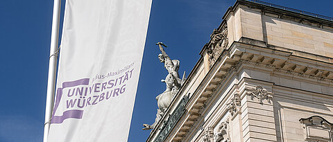 Blick aufs Hauptgebäude der Uni Würzburg mit Uni-Fahne.